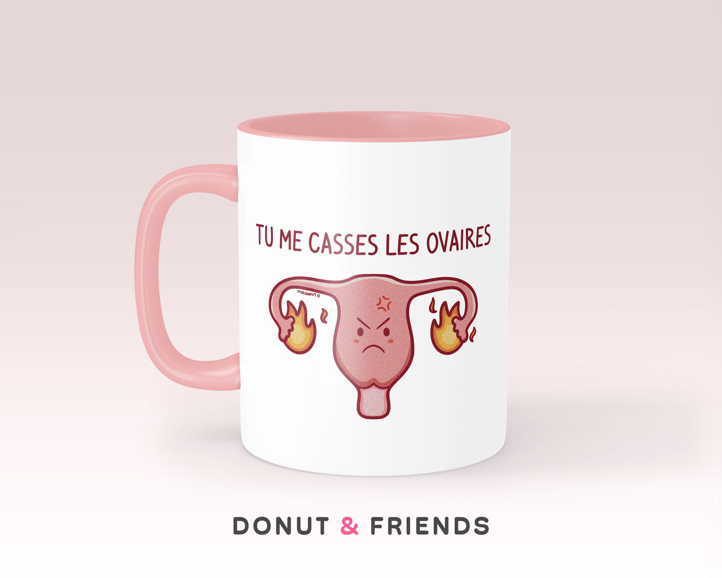 Mug humour tu me casses les ovaires, avec un dessin d'un utérus avec des ovaires en feu. Anse et intérieur rose